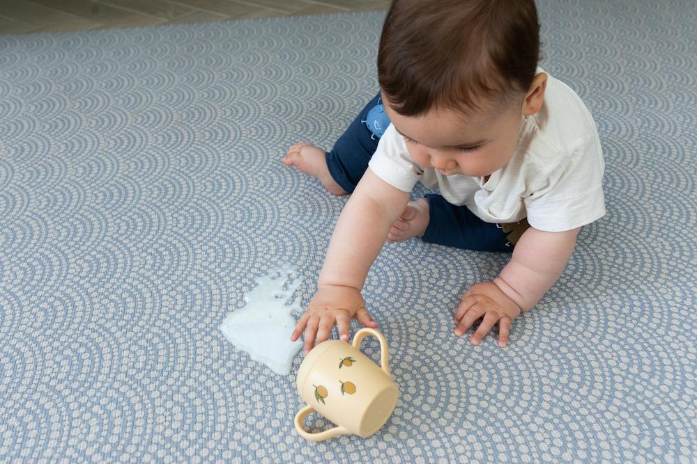 Tapis de jeu "Totter + Tumble" avec bébé assis dessus, lavable à l'eau.